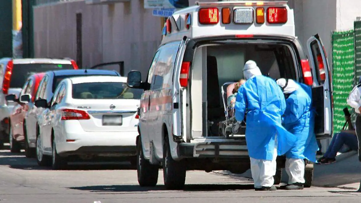 personal con indumentaaria anticovid sube paciente a ambulancia